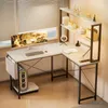 A modern L-shaped computer desk with a monitor, keyboard, and computer tower, set up in a home office environment near a window with blinds. Anteprima dell’immagine prodotto