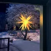 A glowing yellow star-shaped lantern hangs outside a window on a snowy night. Voir les images du produit