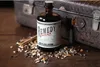 A bottle of Remedy Spiced Rum sits on a wooden surface, surrounded by spices, with a vintage suitcase in the background. Náhled obrázku produktu