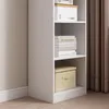 A white bookshelf with books and storage boxes on its shelves, placed next to a curtain. Podgląd zdjęcia produktu
