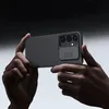 Hands holding a smartphone with a protective case, showcasing the camera cover. Náhľad obrázku produktu