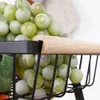 A close-up view of green grapes in a black wire basket with a wooden handle. Anteprima dell’immagine prodotto