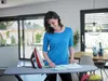 A woman is ironing clothes in a modern living room. Náhled obrázku produktu