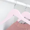 Close-up of pink wooden hangers in a closet, with a pink garment hanging on one. Produktbild-Vorschau