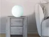 A spherical lamp sits on a wooden nightstand next to a bed. Produktbild-Vorschau