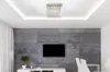 A modern living room with a TV mounted on a concrete-effect wall, a ceiling light, and a white entertainment unit. Produktbild-Vorschau