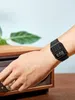 A person's arm wearing a black digital watch is shown adjusting a knob on a wooden electronic device. Produktbild-Vorschau