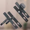 Two black door handles with long plates are displayed diagonally against a blurred background. Náhled obrázku produktu