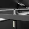 A close-up view of a metal hinge mechanism on a dark-colored surface, likely part of a storage box or furniture. Produktbild-Vorschau