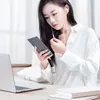 A woman is using a smartphone with an adapter connected to it, while a laptop is on the table. Náhľad obrázku produktu