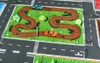 A toy car mat with roads and green grass, featuring two toy cars. Produktbild-Vorschau