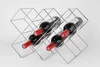 A silver metal wine rack holding four bottles of red wine. Produktbild-Vorschau