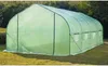 A green tunnel greenhouse is set up on a grassy lawn with trees in the background. Voir les images du produit