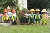 A group of Playmobil figures are arranged in a garden setting, with some figures pushing a wheelbarrow with a plant. Náhľad obrázku produktu
