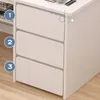 A close-up view of a white computer desk with three drawers, showing the side and front of the drawers. The desk is placed on a wooden floor. Podgląd zdjęcia produktu