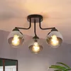 A black ceiling light fixture with three glass globes is shown against a light gray and white background. Produktbild-Vorschau