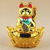 A golden lucky cat figurine sits on a boat-shaped base decorated with coins. Produktbild-Vorschau