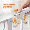 A hand operating a white baby gate with orange arrows indicating the steps to open it. A dog is sleeping behind the gate. Voir les images du produit