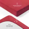 A close-up view of a red fitted sheet, showing its texture and elastic band, with marketing text and icons. Voir les images du produit