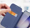 A hand is inserting a credit card into a blue phone case. Voir les images du produit