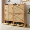 A wooden shoe cabinet with rattan doors and a metal frame, placed in a room with curtains and a plant. Anteprima dell’immagine prodotto