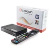 A black satellite receiver, its remote control, and its packaging are arranged on a white background. Produktbild-Vorschau