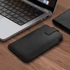 A black phone case with red stitching is placed on a wooden surface next to a laptop. Produktbild-Vorschau