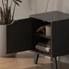 A close-up view of an open black nightstand with items inside. Podgląd zdjęcia produktu