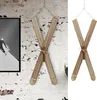A decorative pair of wooden skis, shaped like an 'X', hanging on a textured white brick wall next to a framed black and white picture of a skier. Produktbild-Vorschau