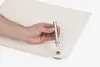 A hand holding a metal tool over a piece of beige fabric with a grommet attached. Produktbild-Vorschau
