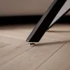 Close-up of a furniture leg with a leveling foot on a wooden floor. Produktbild-Vorschau