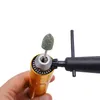 A hand holds a gold-colored rotary tool with a green grinding bit attached to the chuck. Podgląd zdjęcia produktu
