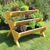 A tiered wooden planter filled with various herbs and lettuces, set in a garden on a sunny day. Produktbild-Vorschau