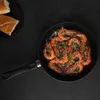 A top-down view of a frying pan filled with cooked shrimp, with bread slices on a black plate to the left, all set against a black background. Produktbild-Vorschau