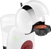 A close-up shot of a white coffee capsule machine with a capsule inserted and a glass of water next to it. Produktbild-Vorschau