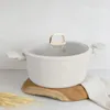 A cream-colored pot with a glass lid and gold accents sits on a wooden board, with wheat stalks in the foreground. Produktbild-Vorschau