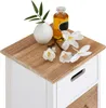 A close-up view of the top of a white and wood-toned chest of drawers, decorated with a small vase of greenery, a bottle of liquid, and white flowers. Produktbild-Vorschau