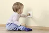 A baby is reaching for an electrical outlet on a wall. Náhľad obrázku produktu