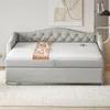 A gray upholstered daybed with a tufted headboard is shown in a room setting with a rug and artwork on the wall. Produktbild-Vorschau