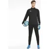 A male model wearing a black Puma tracksuit and holding a soccer ball. Produktbild-Vorschau