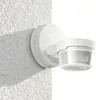 A white motion detector is mounted on a textured white wall. Produktbild-Vorschau