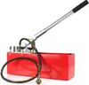 A red hydraulic pressure testing pump with a silver handle and a black hose, isolated on a white background. Náhľad obrázku produktu