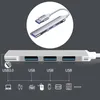 A close-up of a silver USB hub with multiple ports, connected to a white cable. The hub is shown against a dark gray background with a circular inset image showing a closer view of the USB connector and ports. Below the hub, icons represent various devices Produktbild-Vorschau
