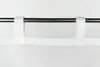 A close-up view of a white curtain with fabric tabs hanging from a dark metal curtain rod against a white background. Produktbild-Vorschau