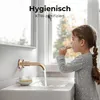 A young girl is brushing her teeth in a bathroom sink with a rose gold faucet running. Anteprima dell’immagine prodotto