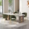 A dining room setting with a marble-topped dining table and four green upholstered chairs with gold legs. Voir les images du produit