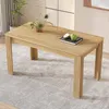 A rectangular wooden dining table with fluted legs is placed on a textured rug in a well-lit room. A small potted plant and a book with two apples are on the table. Náhled obrázku produktu
