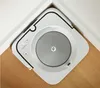 A white robot vacuum cleaner is positioned in the corner of a room, resting on a wooden floor and against white walls. Anteprima dell’immagine prodotto