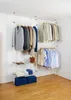 A modular wardrobe system with clothes hanging on it, placed in a room with wooden flooring. Produktbild-Vorschau