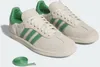 A pair of Adidas Samba sneakers with green accents and a pair of green laces. Produktbild-Vorschau